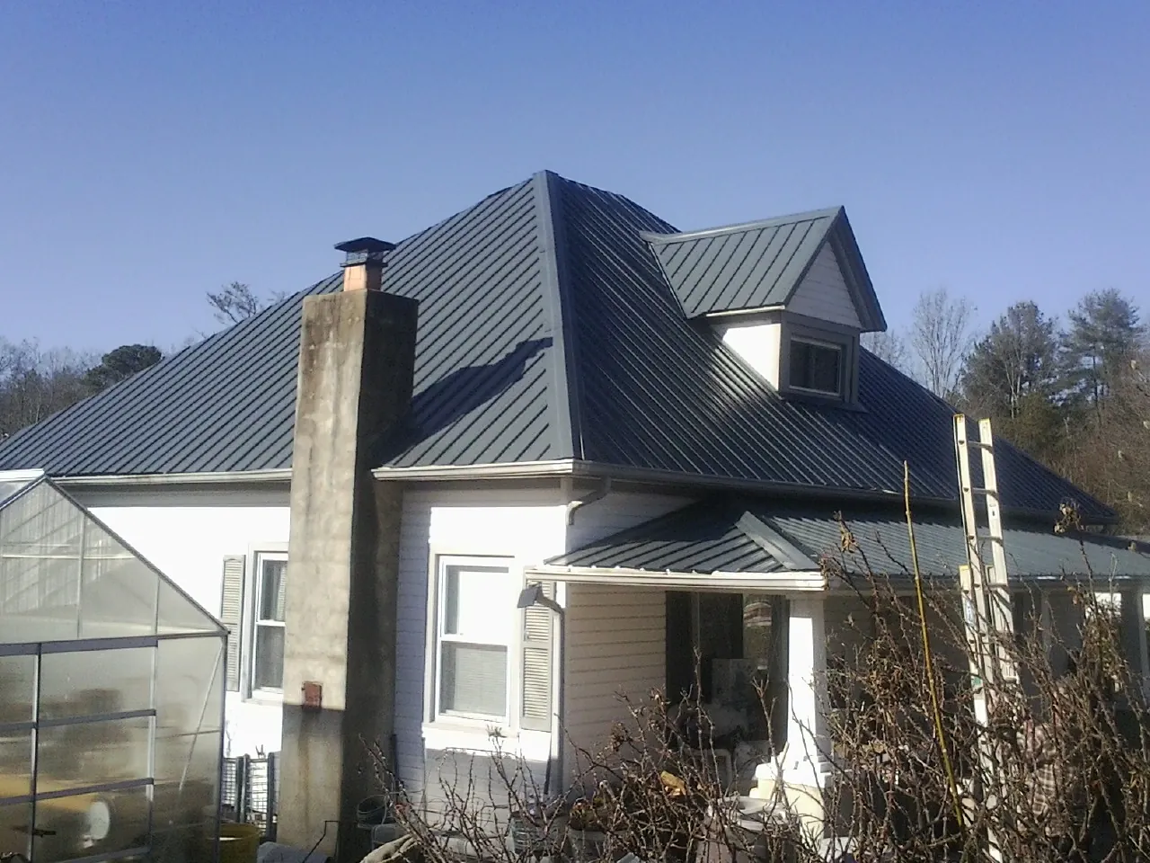 Dark blue standing seam metal roof on a white farmhouse with dormer — Slate & Tile Roof Repair by Roofing Brothers in Fairfax Station
