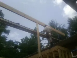 Carpenter setting a ridge beam over a new addition frame — Ice Dam Removal by Roofing Brothers in Fairfax Station