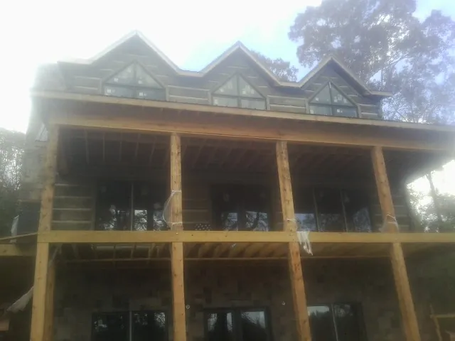 Dormers and porch framing on a large log home under construction — Roof Coating work by our crew in Fairfax Station
