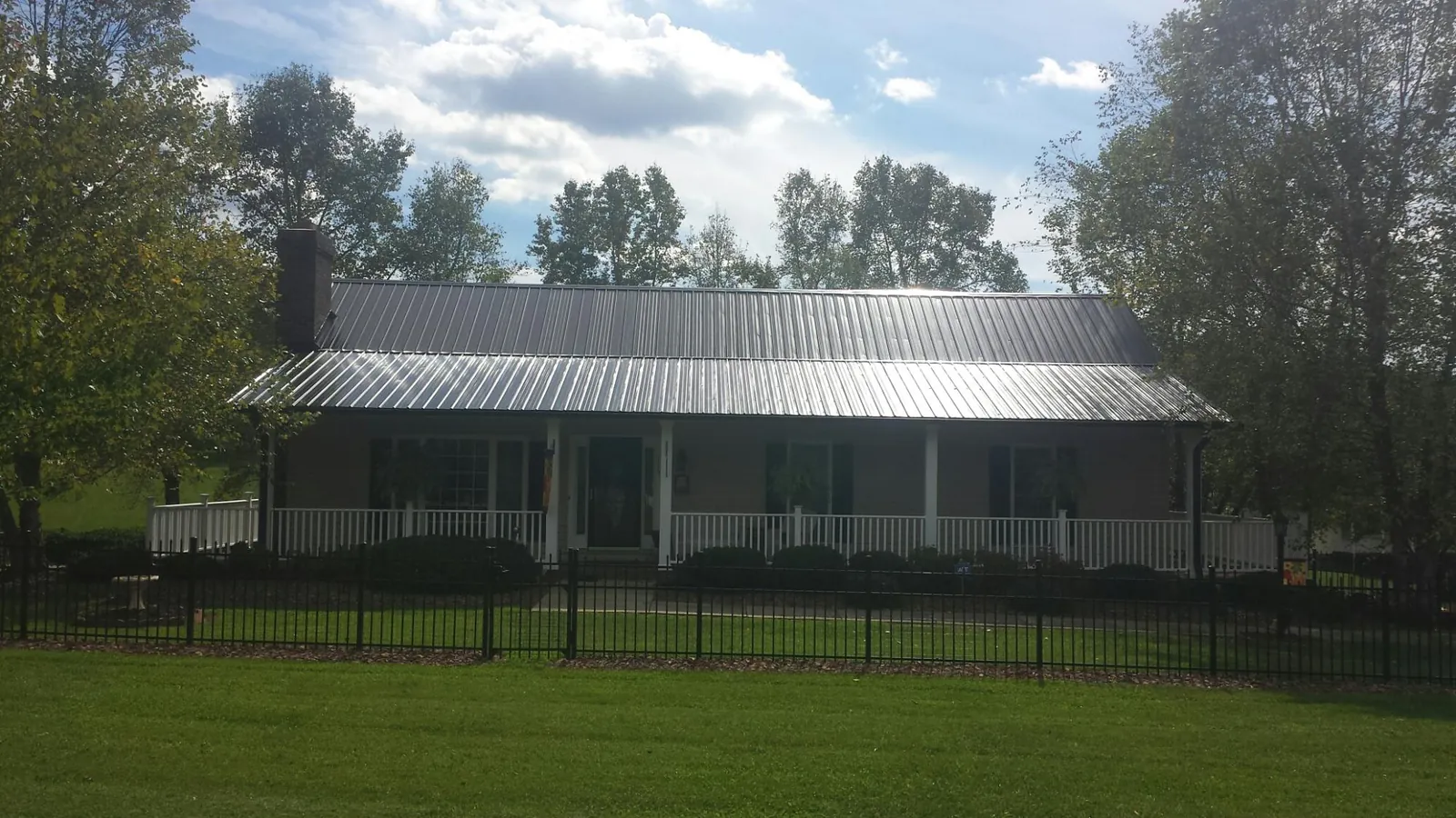 Gray metal roof on a brick ranch with a full width front porch — Gutter Guard Installation work by our crew in Fairfax Station