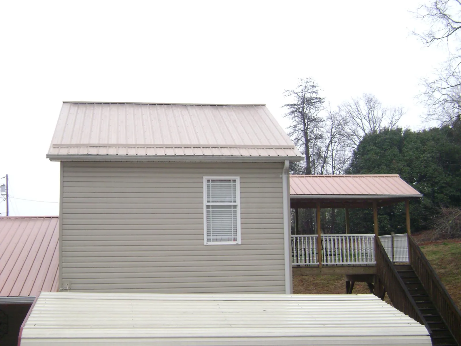 Tan metal roofs on a two story addition and attached porch, from a Roof Replacement job in Fairfax Station