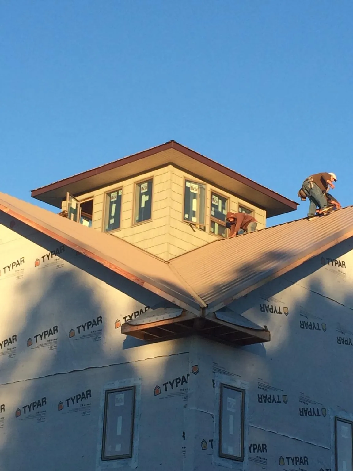 Roofers working around a rooftop cupola on a new metal roof at sunset — Roof Waterproofing in Fairfax Station by Roofing Brothers
